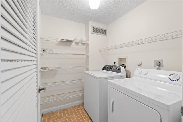 laundry room featuring washing machine and dryer and a textured ceiling