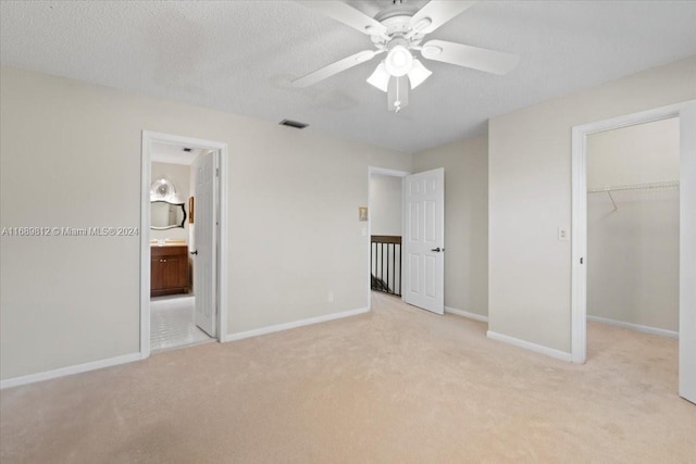 unfurnished bedroom featuring ceiling fan, ensuite bathroom, and light carpet