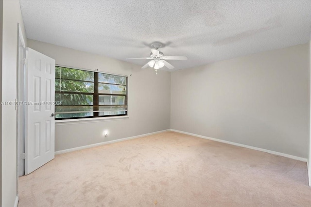 spare room featuring light carpet, a textured ceiling, and ceiling fan