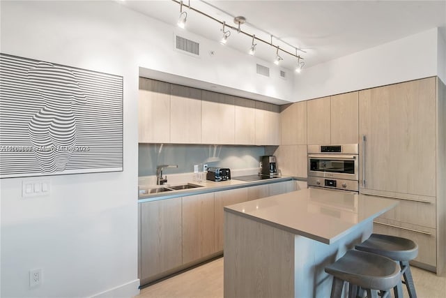 kitchen with a center island, a breakfast bar, sink, and light brown cabinets