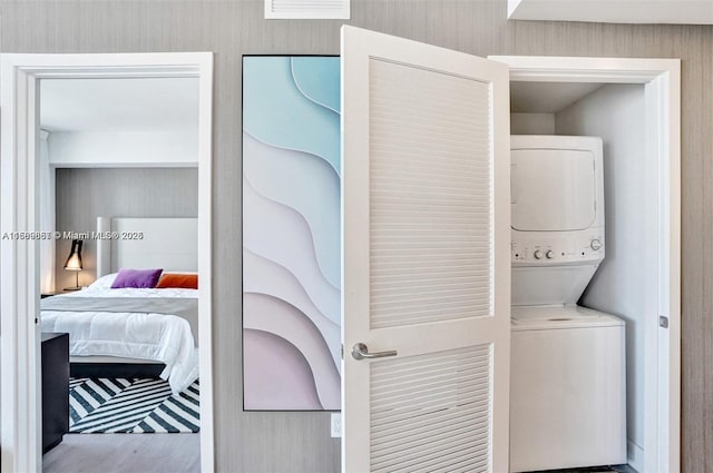 laundry room featuring stacked washer and dryer and wood-type flooring