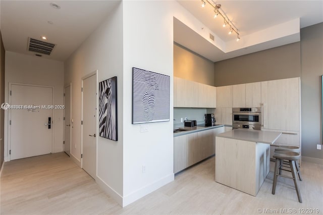 kitchen featuring a center island, oven, light hardwood / wood-style flooring, and a kitchen bar