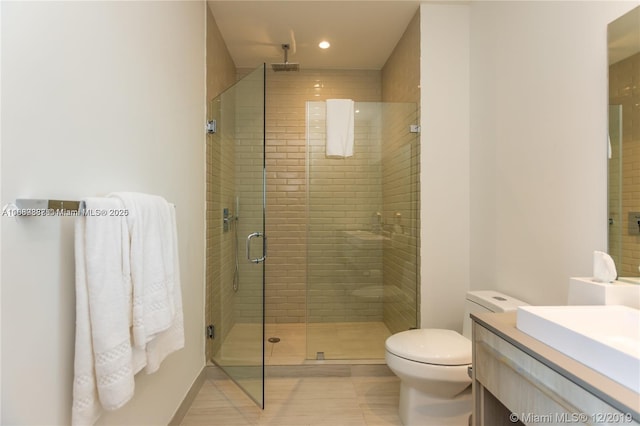 bathroom featuring vanity, a shower with door, and toilet