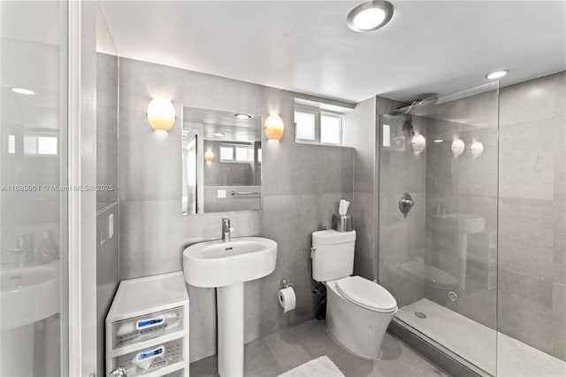 bathroom featuring toilet, a tile shower, and tile walls