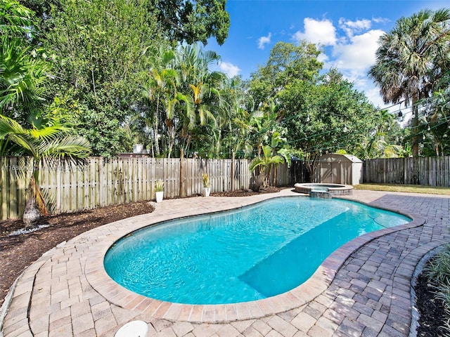 view of pool with a shed and an in ground hot tub