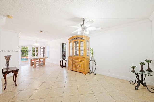 interior space featuring crown molding, a textured ceiling, light tile patterned floors, and ceiling fan