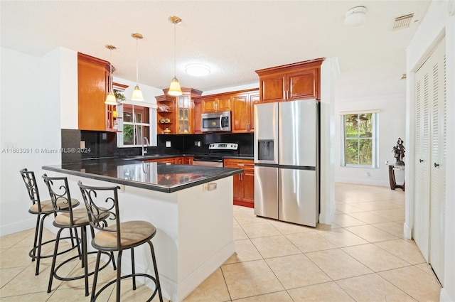 kitchen featuring backsplash, appliances with stainless steel finishes, decorative light fixtures, sink, and a kitchen breakfast bar