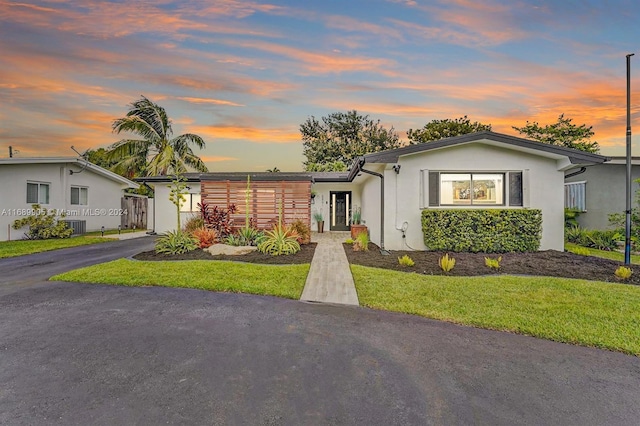 view of front of house featuring a lawn and central AC unit