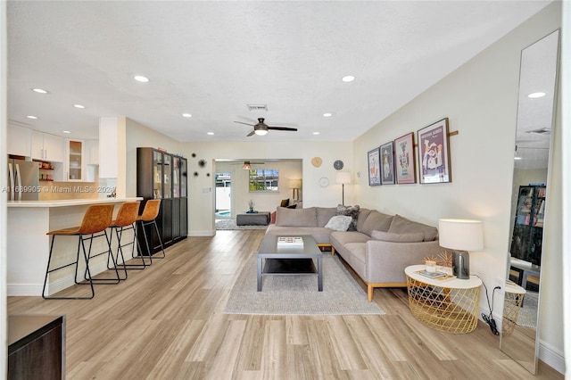 living room featuring a textured ceiling, light hardwood / wood-style floors, and ceiling fan