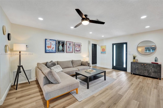 living room featuring a textured ceiling, light hardwood / wood-style flooring, and ceiling fan