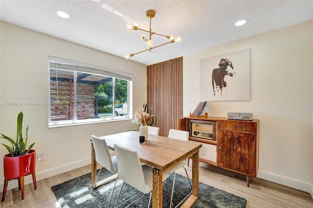 dining room featuring a chandelier, a textured ceiling, and light hardwood / wood-style flooring