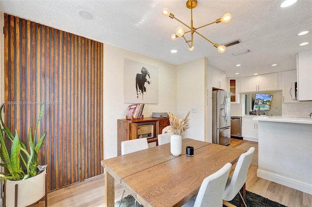 dining room featuring a textured ceiling, light hardwood / wood-style floors, and an inviting chandelier