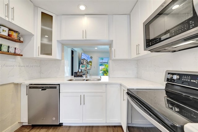 kitchen with appliances with stainless steel finishes, dark hardwood / wood-style floors, white cabinetry, and sink