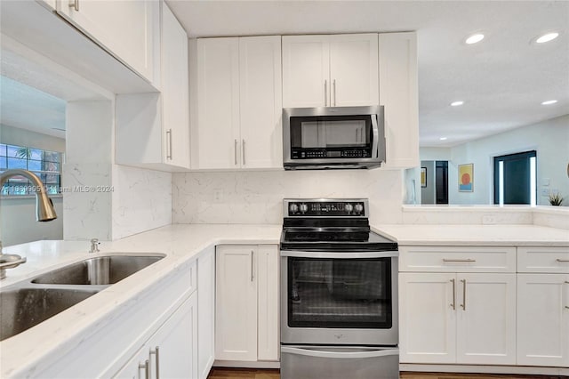 kitchen with white cabinets, decorative backsplash, sink, and stainless steel appliances