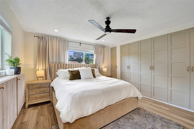 bedroom featuring ceiling fan, a textured ceiling, and light hardwood / wood-style flooring