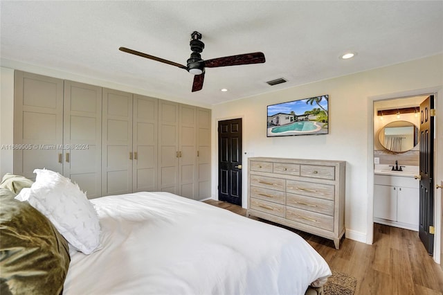 bedroom featuring ensuite bathroom, a textured ceiling, ceiling fan, sink, and wood-type flooring