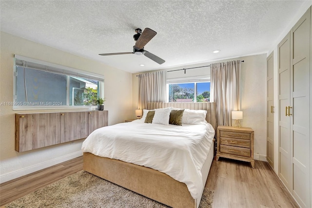 bedroom with ceiling fan, light hardwood / wood-style floors, and a textured ceiling