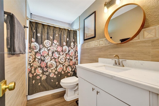 bathroom with toilet, vanity, tile walls, and hardwood / wood-style flooring