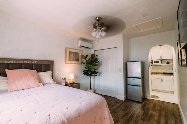 bedroom with ceiling fan, dark hardwood / wood-style flooring, a wall unit AC, stainless steel fridge, and a closet