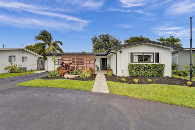 ranch-style home with a front yard and central AC