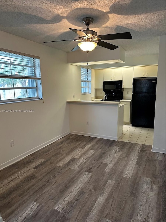 kitchen featuring hardwood / wood-style flooring, plenty of natural light, black appliances, white cabinets, and kitchen peninsula