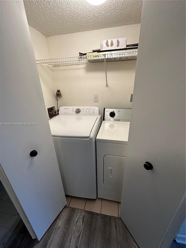 laundry room featuring hardwood / wood-style floors, a textured ceiling, and washing machine and clothes dryer