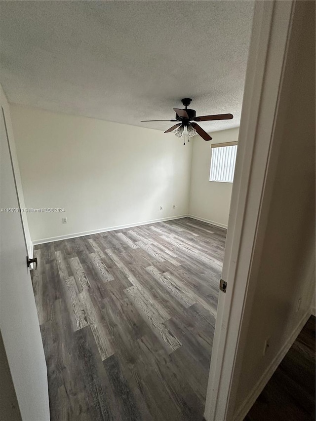 unfurnished room featuring dark hardwood / wood-style floors, ceiling fan, and a textured ceiling