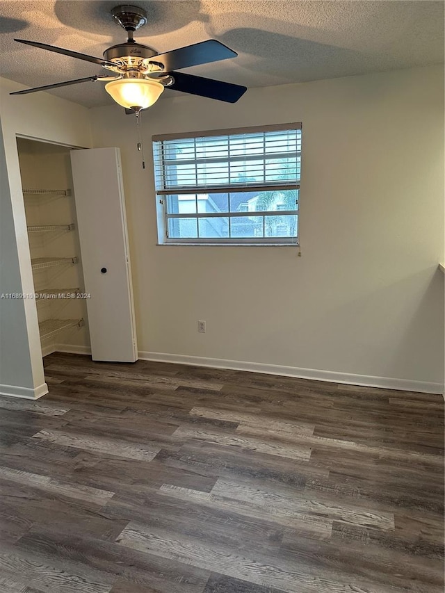 unfurnished bedroom featuring ceiling fan, dark hardwood / wood-style flooring, a textured ceiling, and a closet