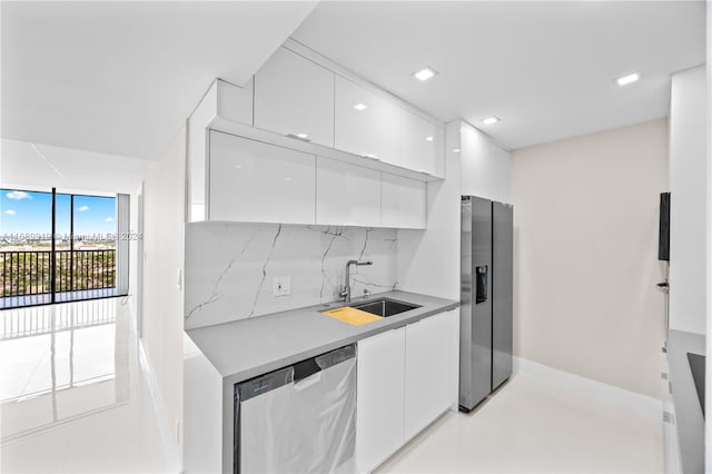 kitchen with backsplash, stainless steel appliances, white cabinetry, and sink