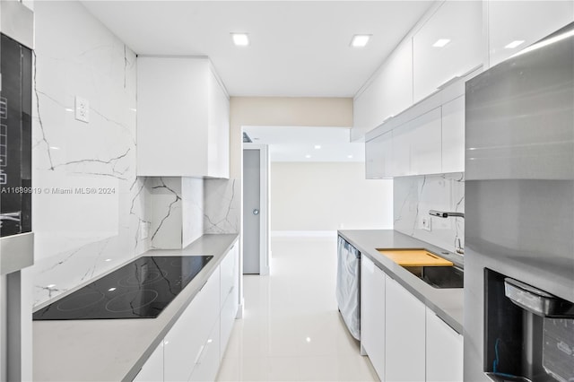 kitchen featuring decorative backsplash, appliances with stainless steel finishes, sink, light tile patterned floors, and white cabinetry