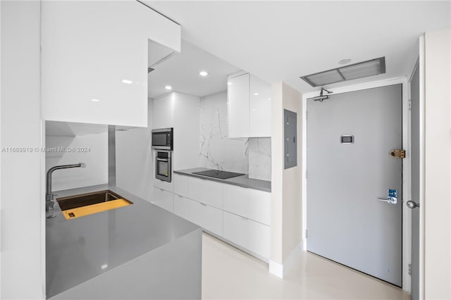 kitchen featuring backsplash, stainless steel appliances, sink, white cabinets, and electric panel