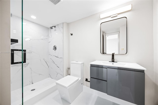 bathroom featuring a tile shower, vanity, and toilet