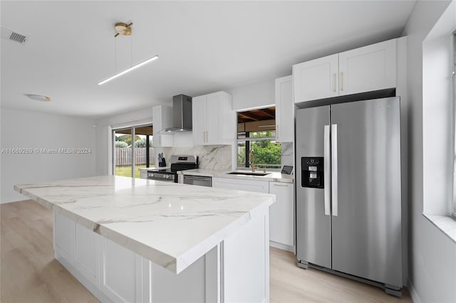 kitchen with wall chimney exhaust hood, white cabinetry, sink, and appliances with stainless steel finishes