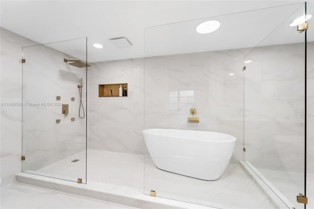 bathroom with shower with separate bathtub and tile walls