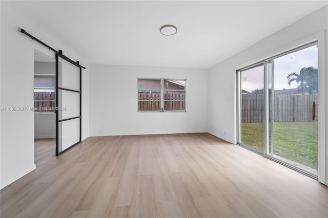 unfurnished room with a barn door and light hardwood / wood-style flooring