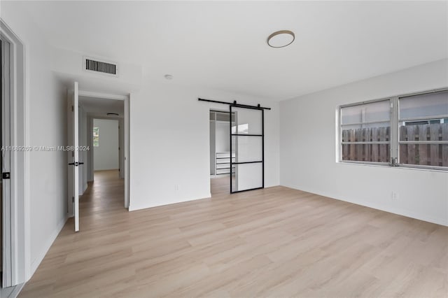 empty room with a barn door and light hardwood / wood-style flooring