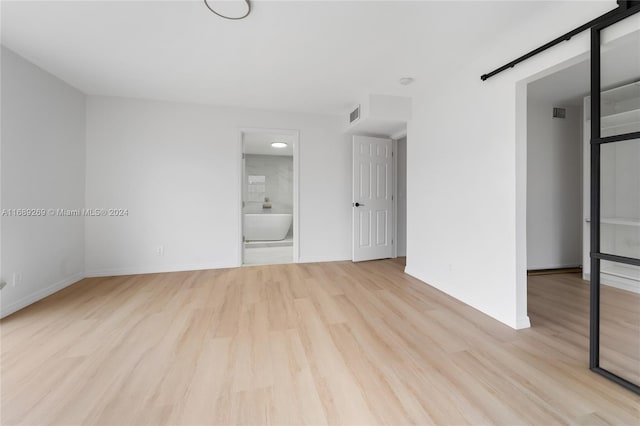 empty room featuring light wood-type flooring and a barn door