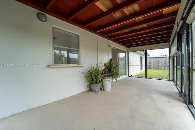 unfurnished sunroom featuring wooden ceiling and beam ceiling