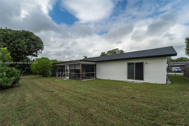 rear view of property with a sunroom and a yard