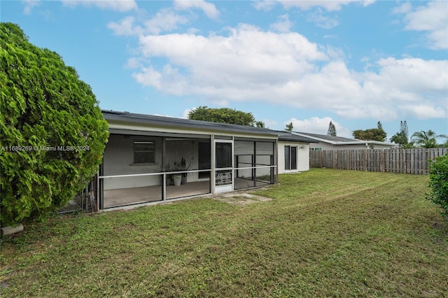 rear view of house featuring a sunroom and a lawn