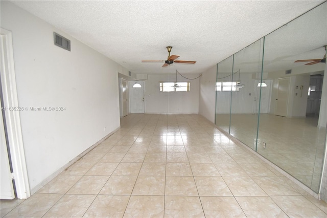 unfurnished room with ceiling fan, a textured ceiling, and light tile patterned floors