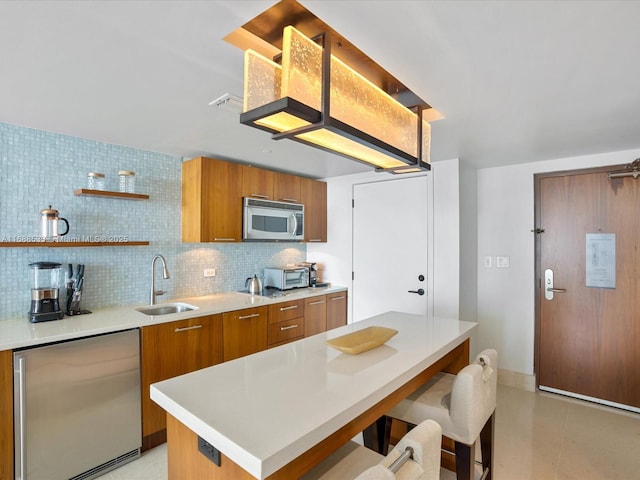 kitchen with open shelves, brown cabinetry, appliances with stainless steel finishes, and a sink