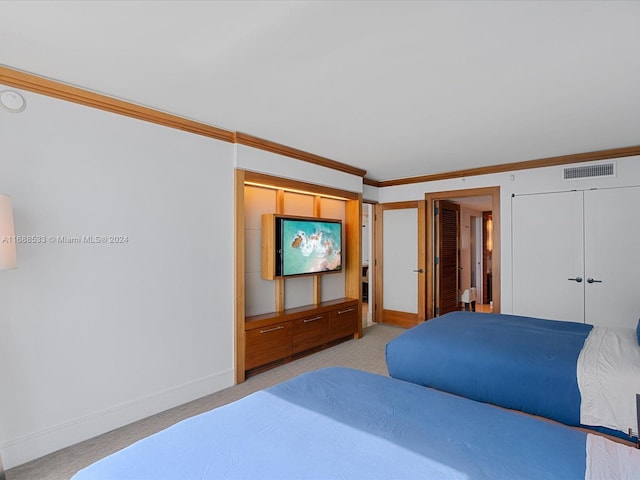 carpeted bedroom with crown molding and a closet