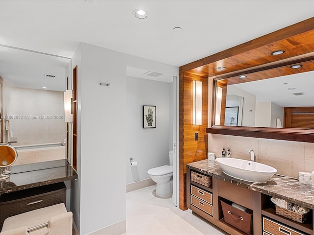full bathroom featuring toilet, tasteful backsplash, baseboards, recessed lighting, and vanity