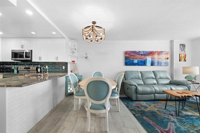 interior space with stainless steel appliances, hardwood / wood-style flooring, white cabinetry, and kitchen peninsula