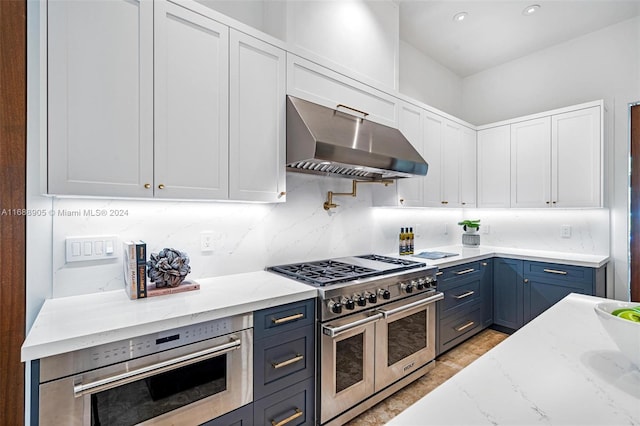 kitchen with stainless steel appliances, light stone counters, tasteful backsplash, range hood, and white cabinets