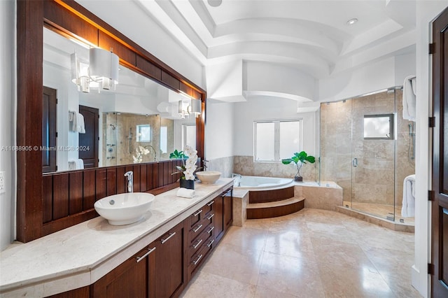 bathroom with a notable chandelier, vanity, a raised ceiling, and separate shower and tub