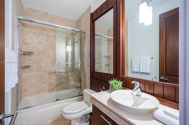 full bathroom with bath / shower combo with glass door, vanity, toilet, and tile patterned flooring