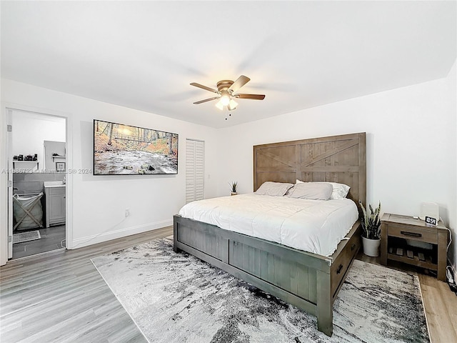 bedroom featuring light wood-type flooring, ceiling fan, and connected bathroom