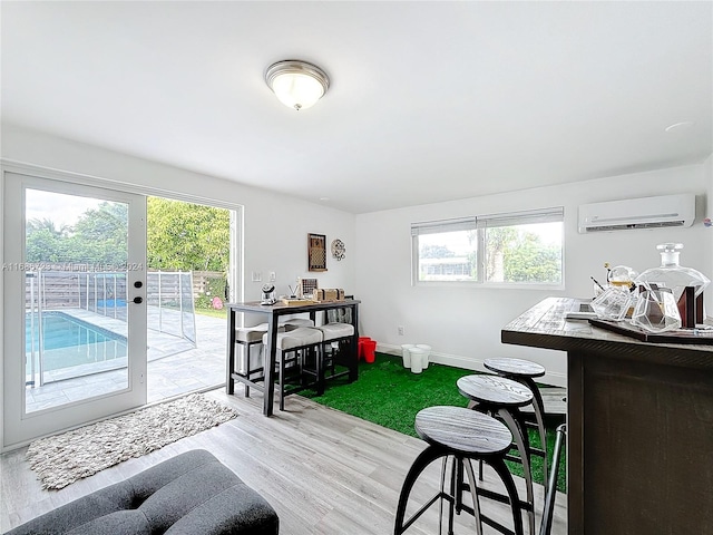 interior space with hardwood / wood-style flooring, an AC wall unit, and a healthy amount of sunlight